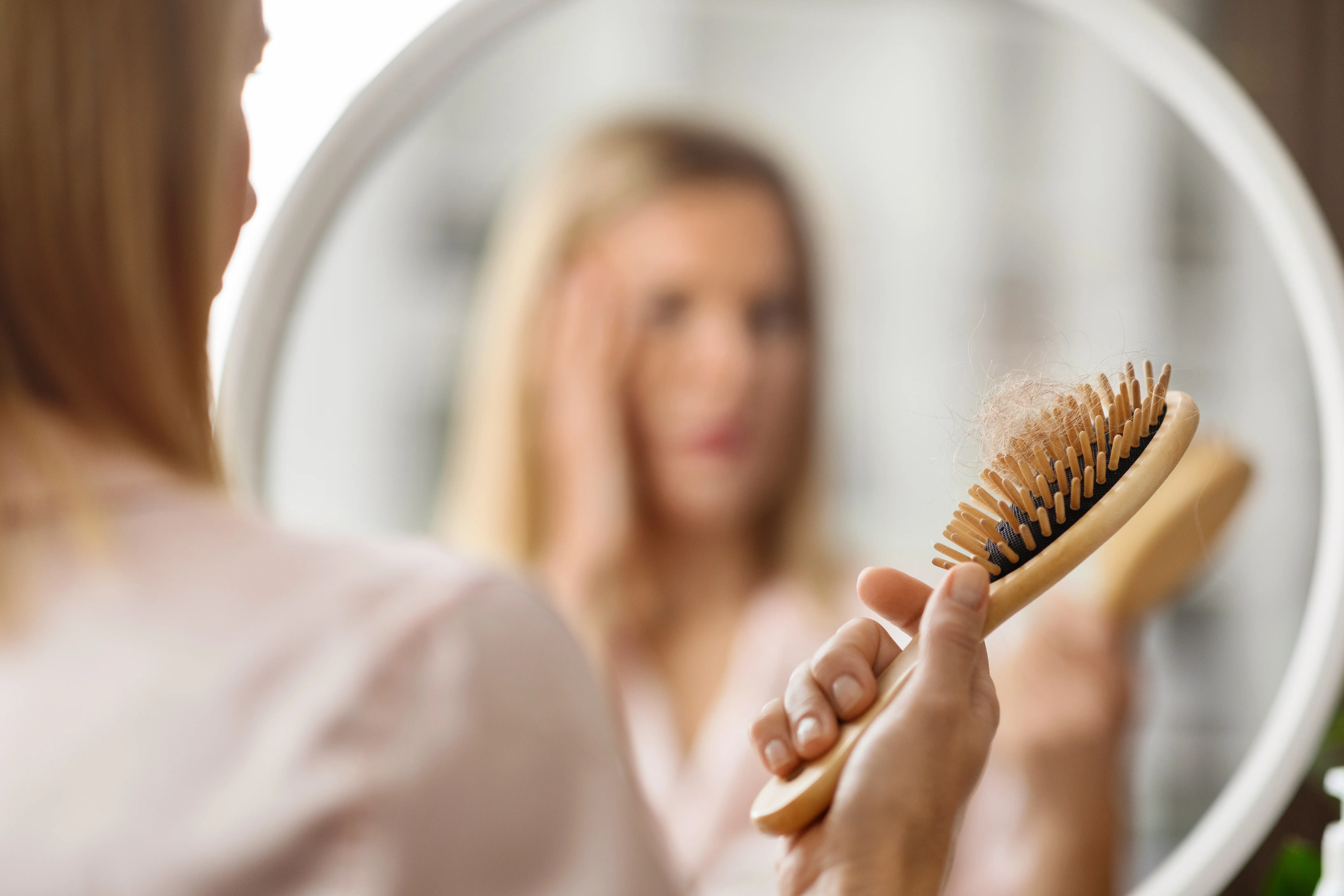 hairloss-shocked-blonde-woman-holding-comb-full of hair